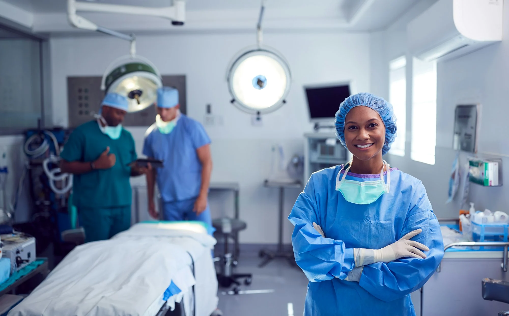 Portrait Of Female Surgeon Wearing Scrubs And Protective Glasses In Hospital Operating Theater